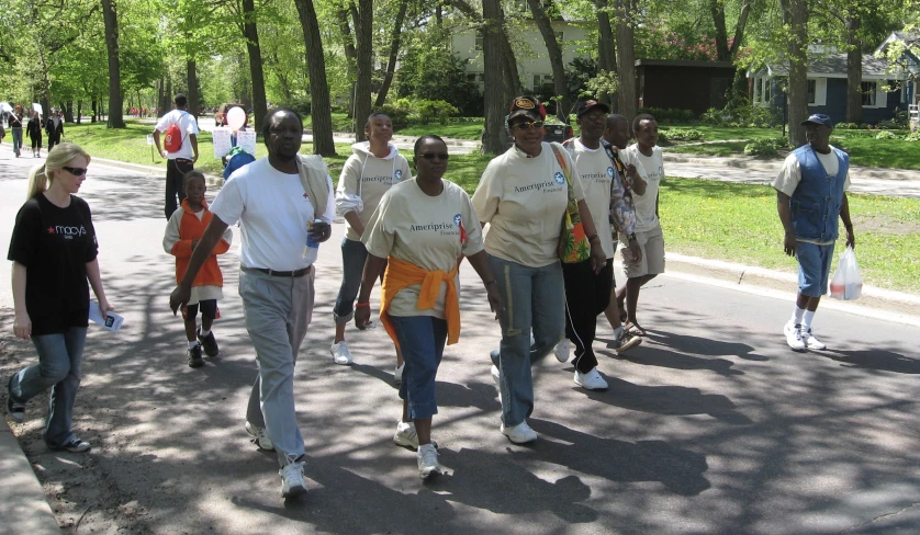 group of people walking down the road on a sunny day