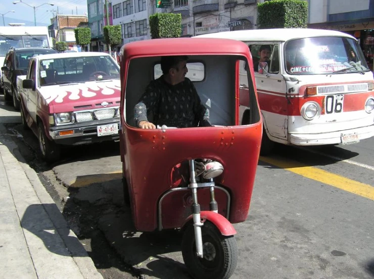 an old red and white truck sitting on a street next to other cars