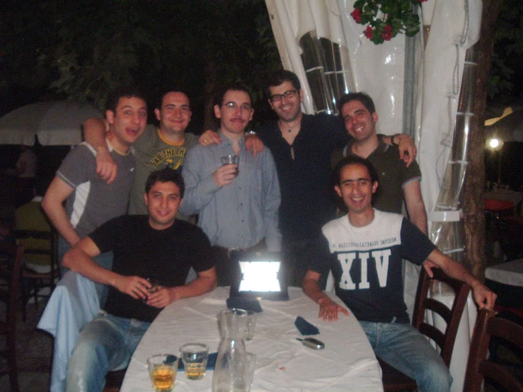 a group of men standing around a white table