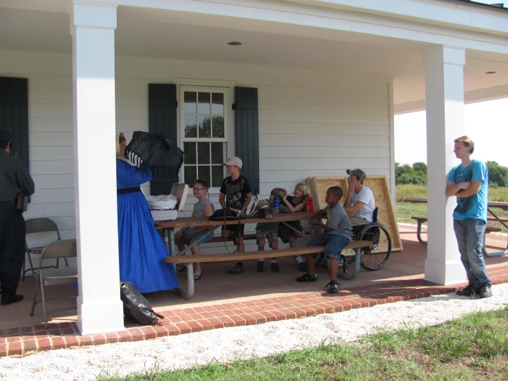 people sitting on porch chairs with a person standing up and one man taking a po