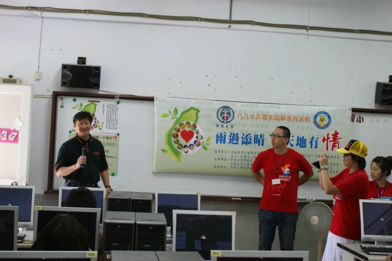 a couple of people standing next to each other in front of a laptop computer