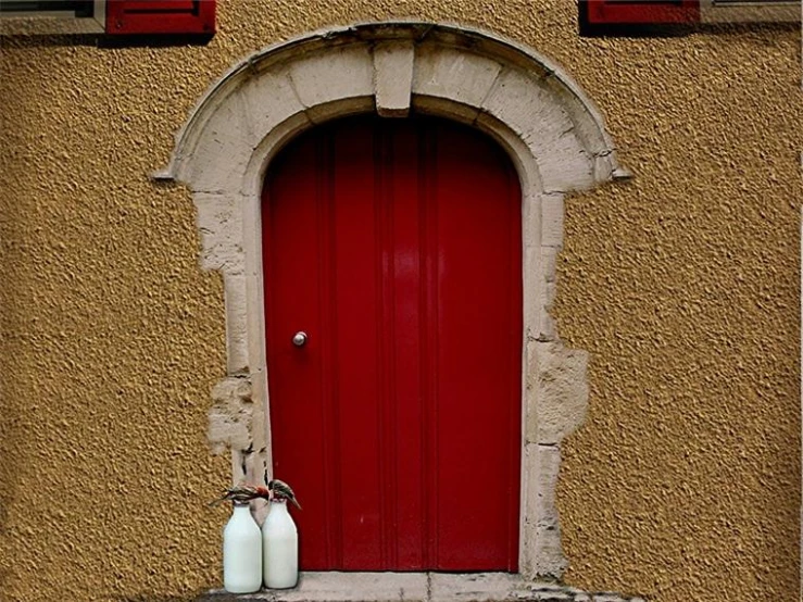 two small white bottles of milk next to an old red door