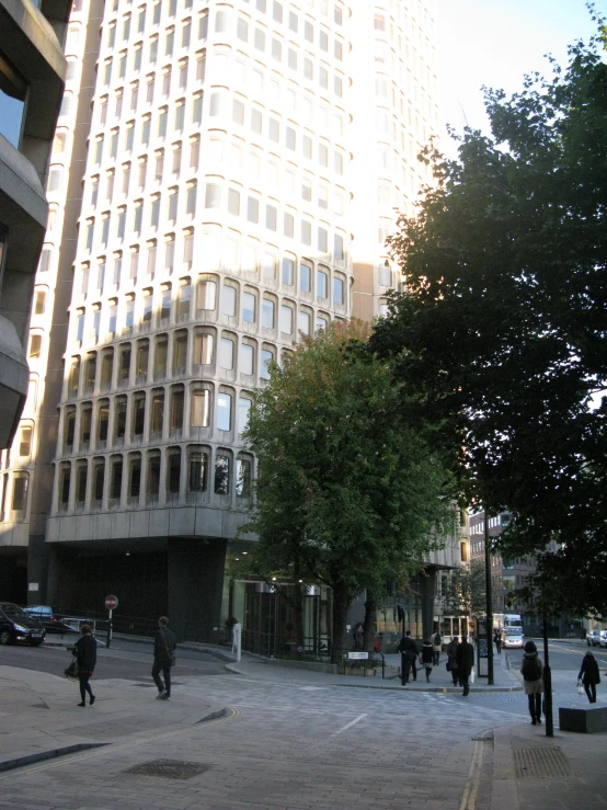 people walking around a small square with a tall white building behind