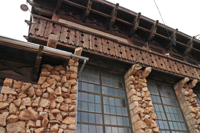 wooden building with stone walls and a lot of windows