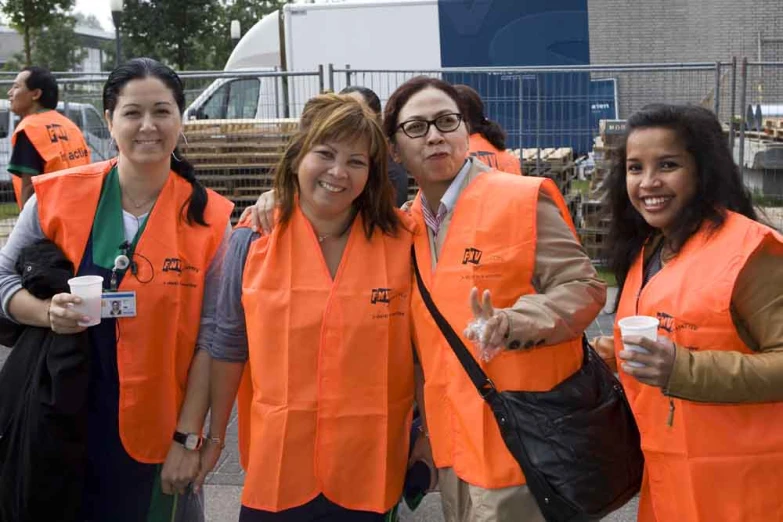 group of women in orange vests standing together and smiling at the camera