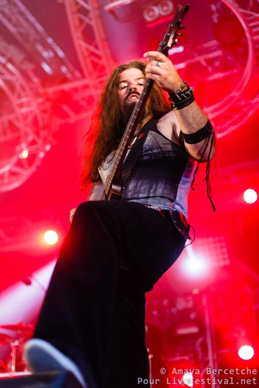 man with long hair on stage playing guitar