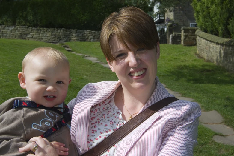 a woman holding a baby while smiling