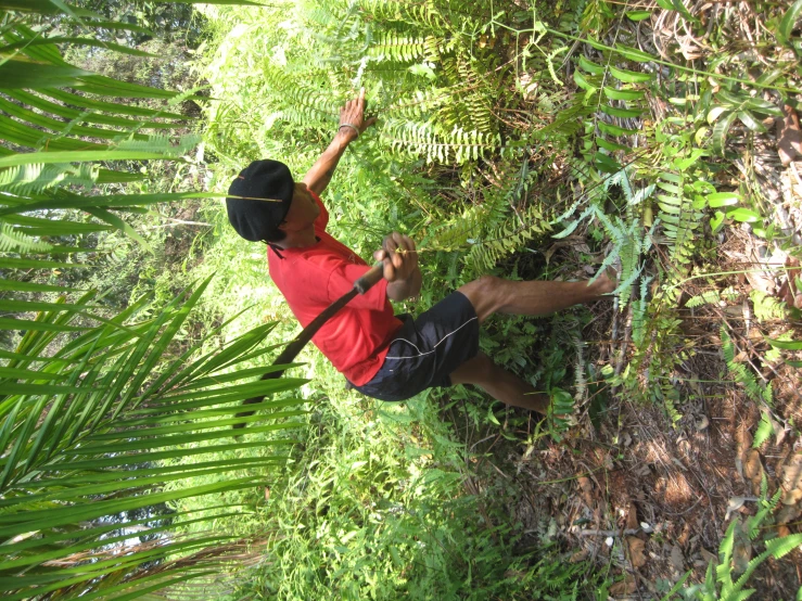 a man in red shirt and black shorts holding a black frisbee