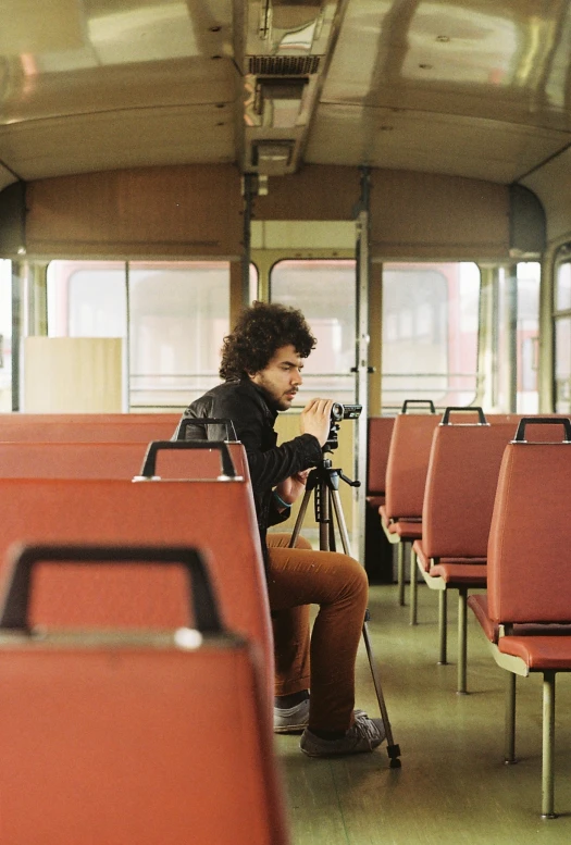 a woman is sitting on the train next to a tripod taking pos