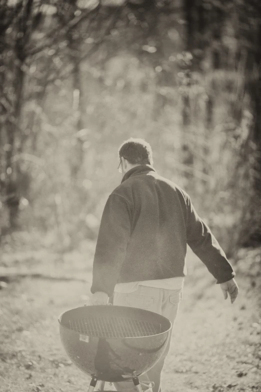 a man pulling a round barbecue with two large grills on it