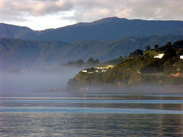 a lake with some hills and houses in the background