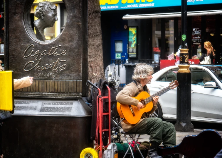 a man is playing guitar on the street