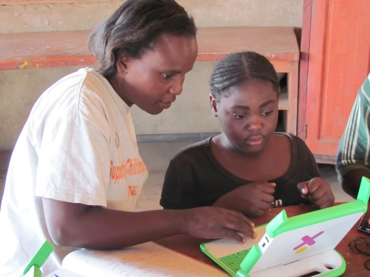 two women are looking at a laptop together