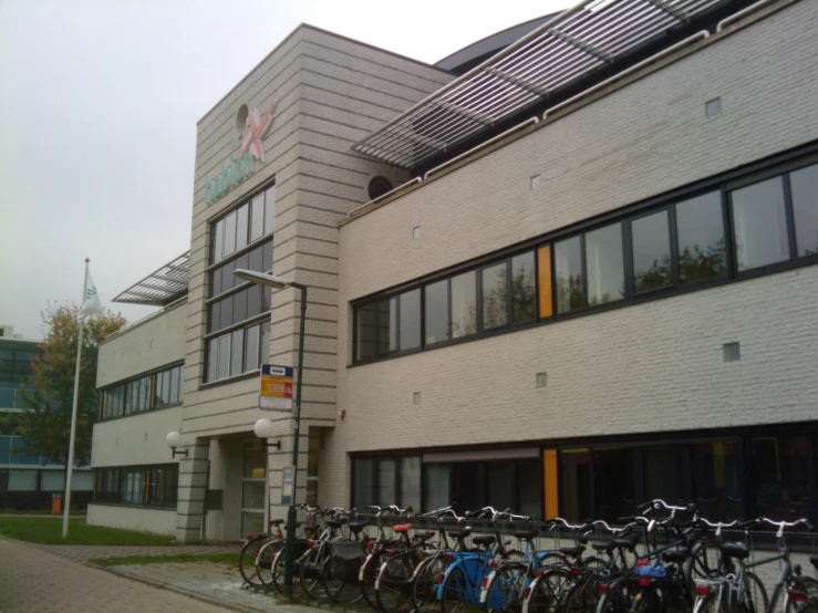 bicycles are lined up next to the parking meters in front of an office building