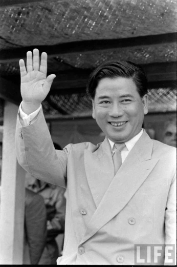 a man in a suit waves at the camera