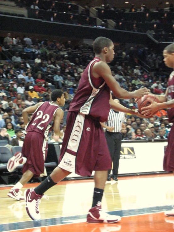 two men in maroon jerseys are holding each other's hands in a basketball game