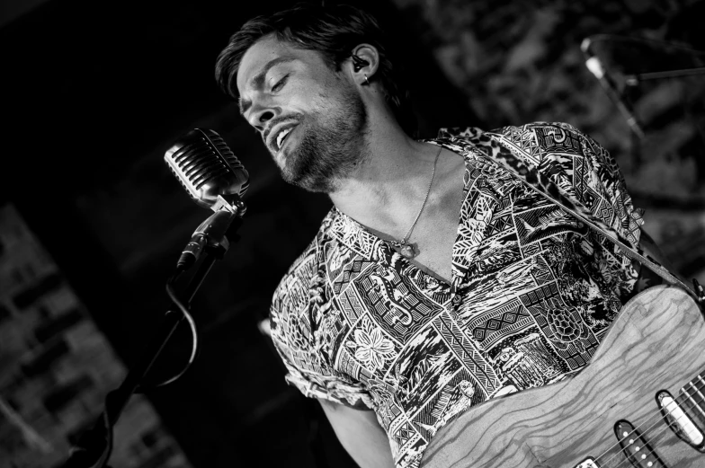 a man playing guitar in a black and white po