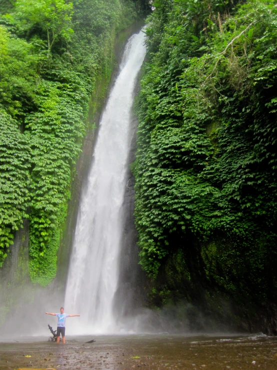a person standing next to a waterfall in a forest