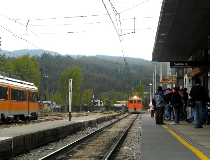several people waiting for a train at a train station