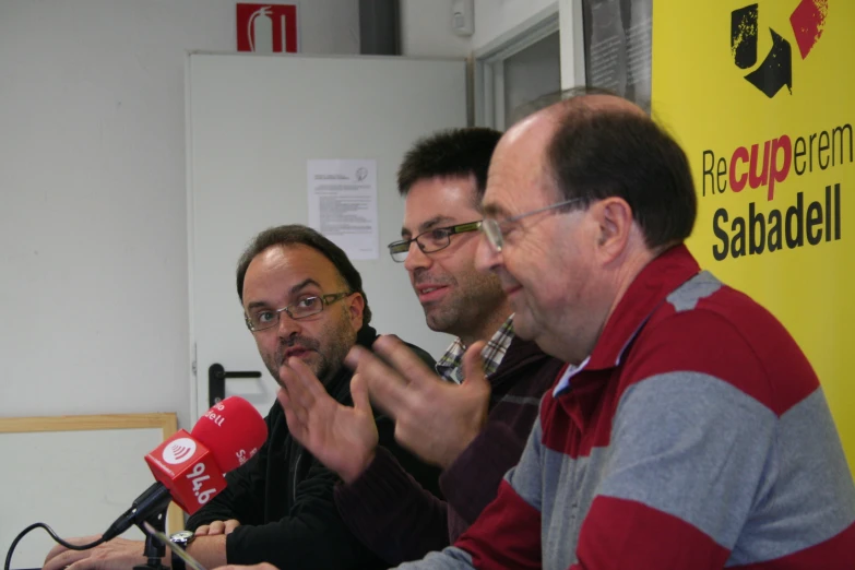 three men are sitting and talking next to each other