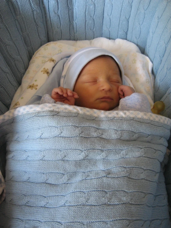 a baby laying in a crib with his head on his hand