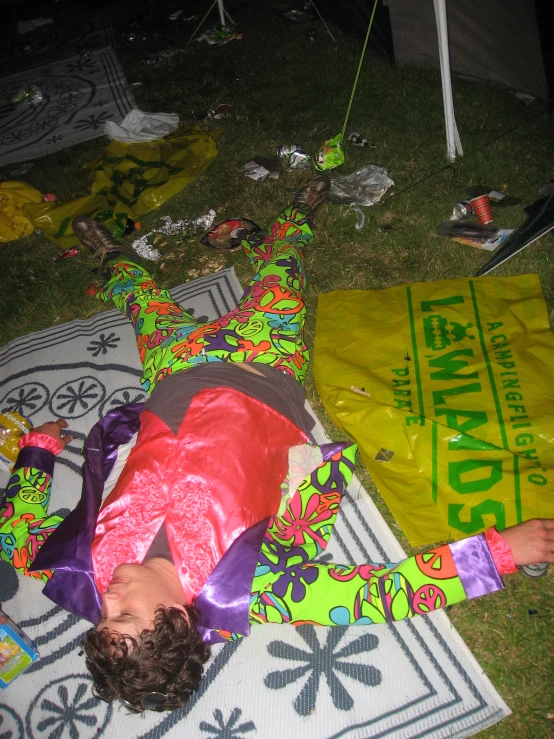 a person is laying on the grass by a bag