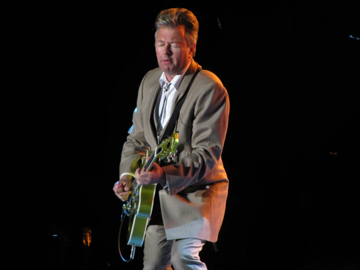 a man with a suit and tie standing in front of a dark stage