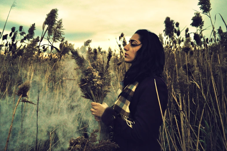 a young woman in black jacket looking at plants