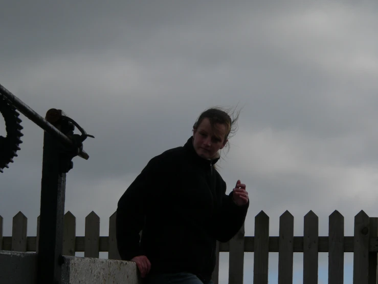 woman smoking cigarette in the foreground behind a fence