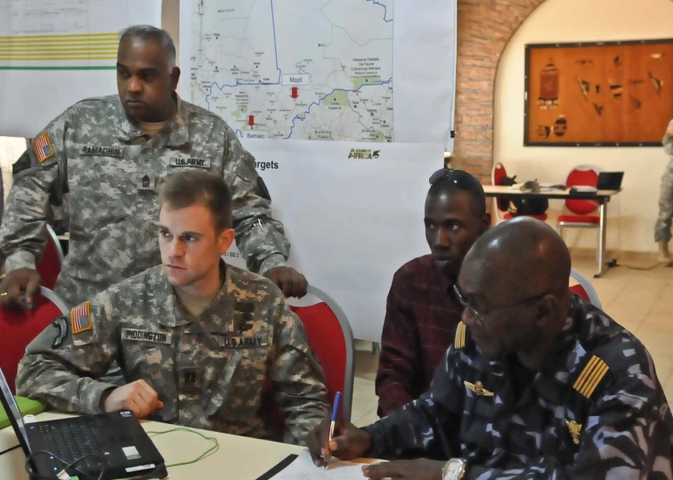 a soldier in a military uniform looks at someone on the laptop screen