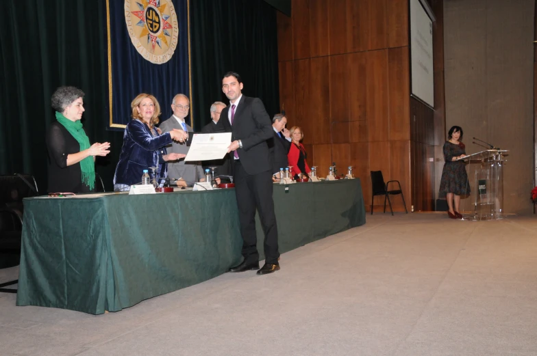 a man standing in front of a green table with several other people