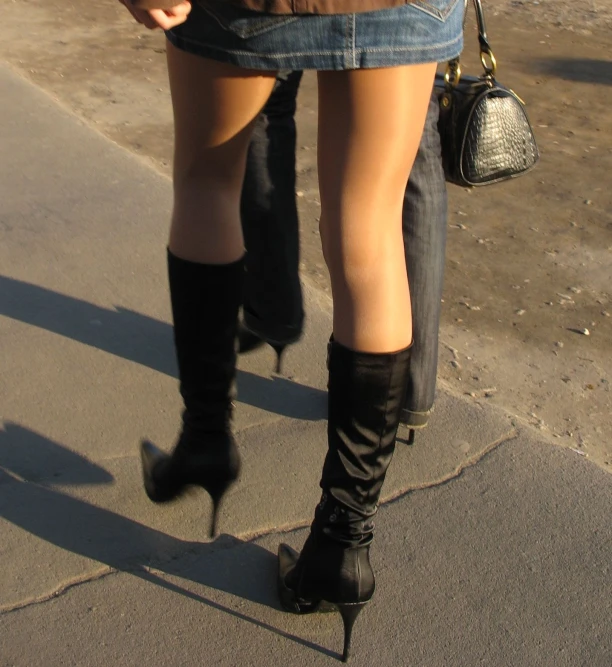 a person walking with a purse and high heel boots on