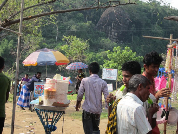 men and women standing in the dirt with umbrellas