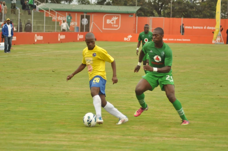 men are in a field playing soccer and people in yellow jerseys