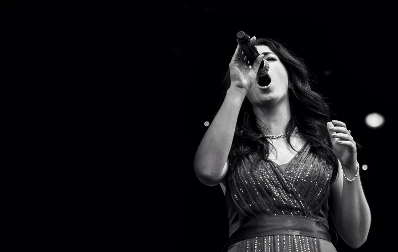 a woman in a very long dress singing into the microphone