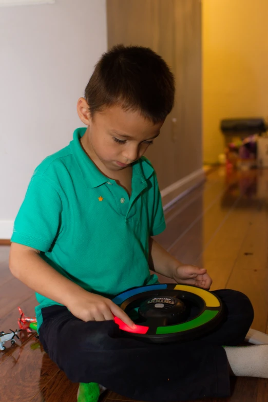 a boy in a green shirt sitting on the floor with a frisbee