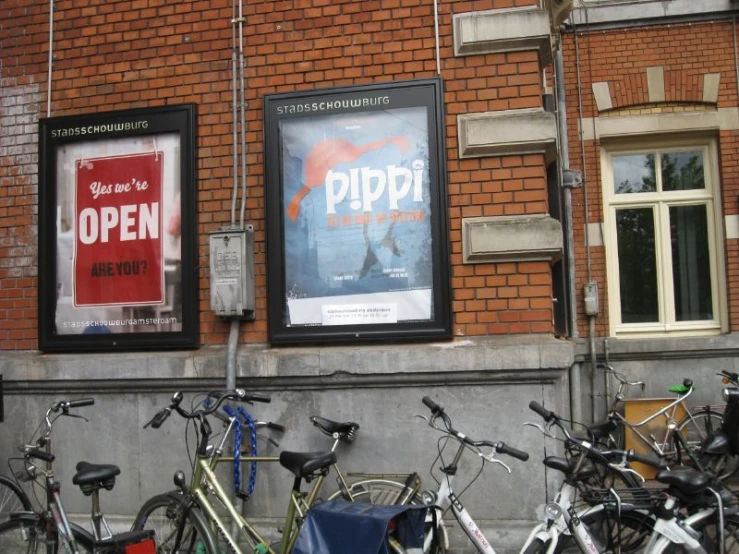 several bicycles are parked in front of a building with posters