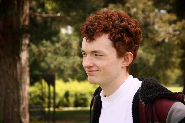 a young man standing next to a tree