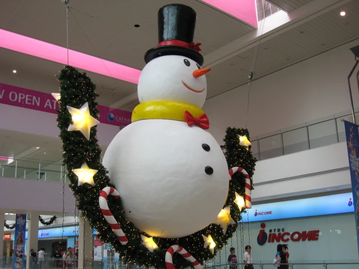 an inflatable snowman and garland are sitting in a shopping mall