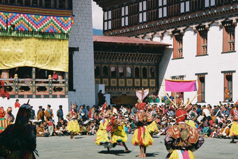 a large crowd is watching two dancers performing on a stone field