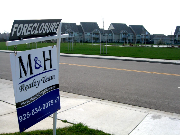 a sign advertising the real estate for sale on the sidewalk