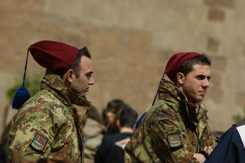 two young soldiers standing together and wearing red caps
