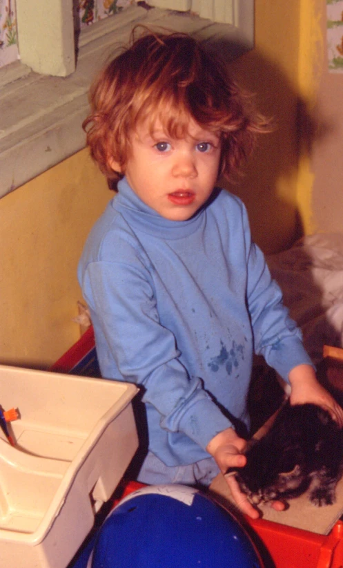 a small child sits on a table as someone combs it