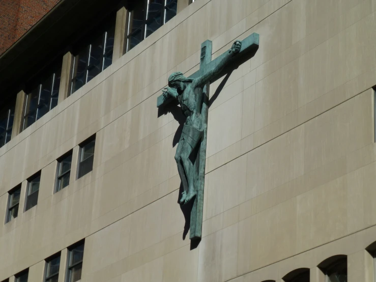 statue on the side of a building holding a cross