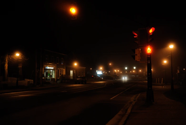 the lights are glowing red at night on the side of the road