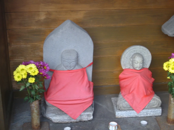 some statues in a line next to flowers