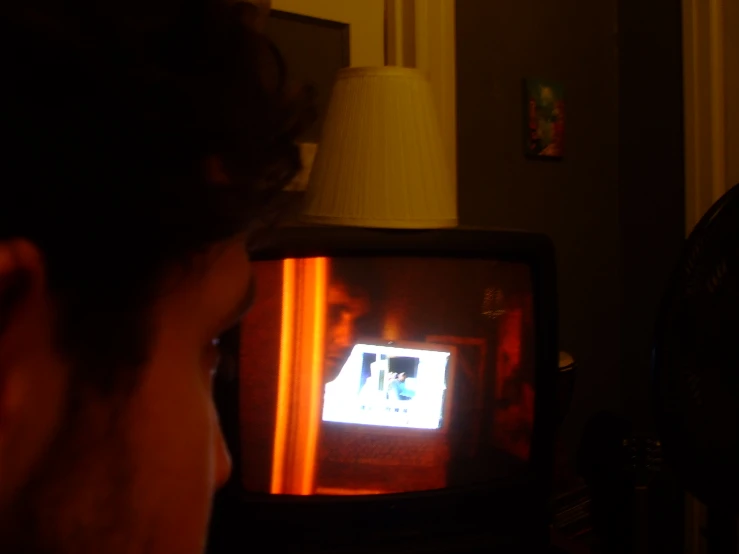 a man staring at a tv that is on