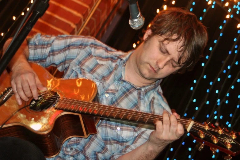 a man is holding his guitar and a microphone