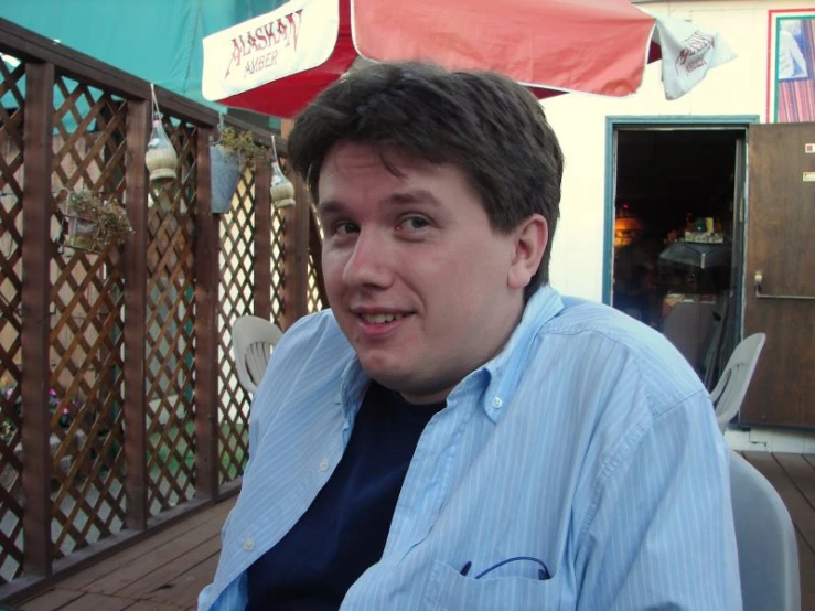 a man with a blue shirt smiles for the camera