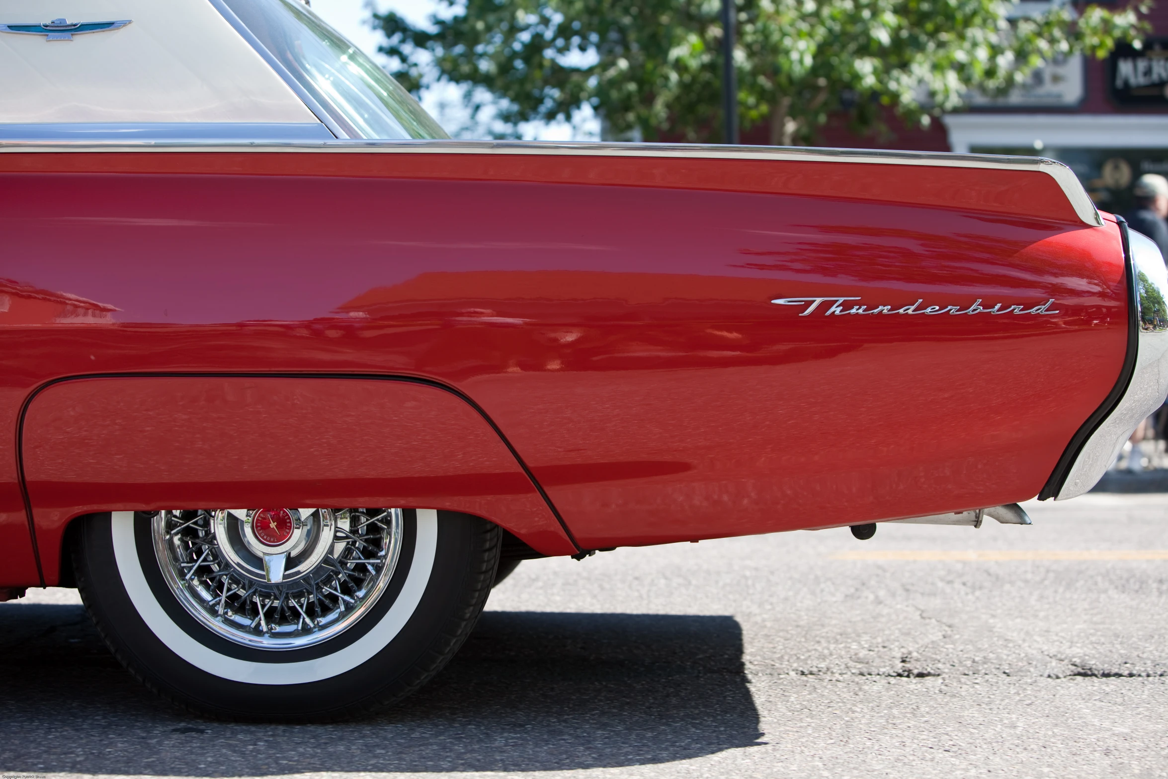 a classic car parked at the curb with people